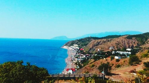 Scenic view of sea and mountains against clear blue sky