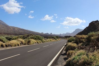 Road leading towards mountains against sky