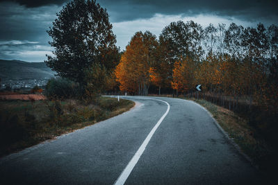 Road amidst trees against sky during autumn