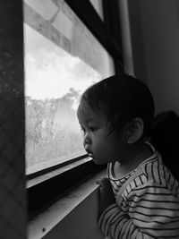 Portrait of girl looking through window