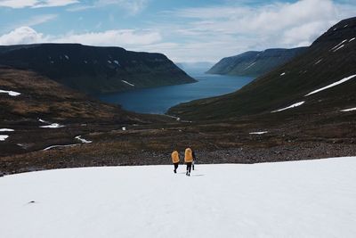 People walking on snowcapped mountains against sky