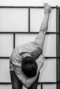 Man posing while standing against wall