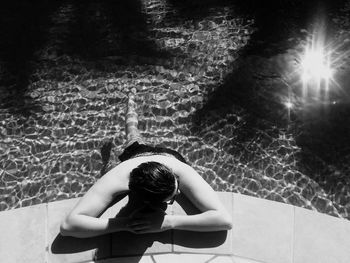 High angle view of shirtless man relaxing in swimming pool