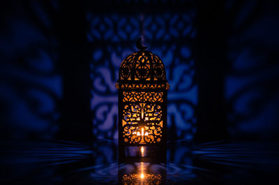 Black lantern with reflection from blue background for ramadan kareem.