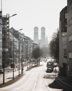 Cars on road by buildings against clear sky