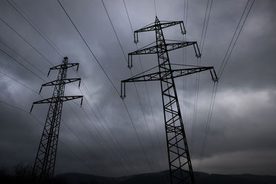 Low angle view of silhouette electricity pylon against sky