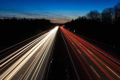 Light trails on road against sky at night