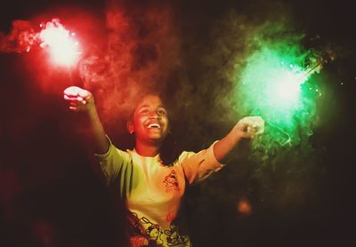 Cheerful teenage girl holding sparklers at night