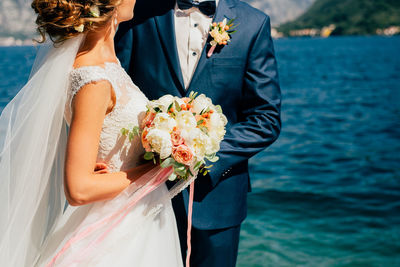 Woman holding flower bouquet near sea