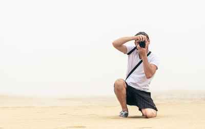 Full length of man photographing on beach
