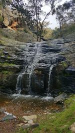 Scenic view of waterfall in forest against sky