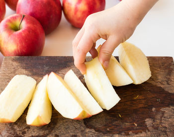 Close-up of hand holding fruits on cutting board