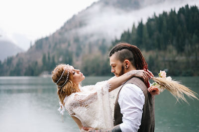 A happy couple in love and married embrace in nature by the lake and the misty mountains