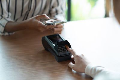 Midsection of woman using mobile phone on table