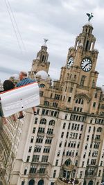 Rear view of people on amusement park ride against royal liver building