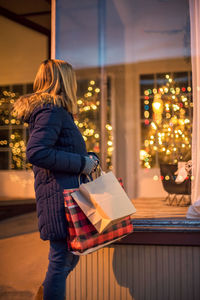 Rear view of woman standing on illuminated christmas tree