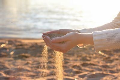 Cropped hands holding sand at beach