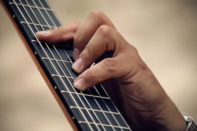 Cropped hand of man playing guitar outdoors