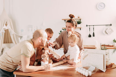 Happy big family of mom dad two kids cooking together and having fun in the kitchen at home