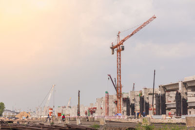 Cranes at construction site against sky