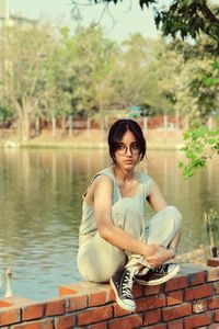 Portrait of young woman standing by lake