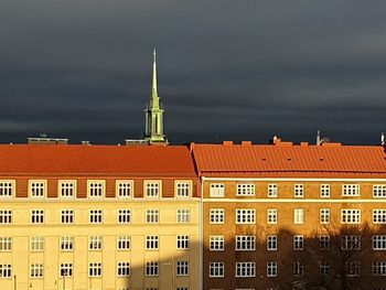 Buildings in city against cloudy sky