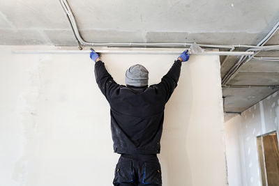Rear view of man standing against wall