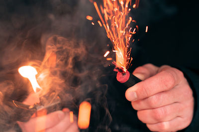 Midsection of person holding sparkler at night