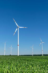 Five wind power turbines, part of a wind farm, on a green field near cottbus, brandenburg, germany.