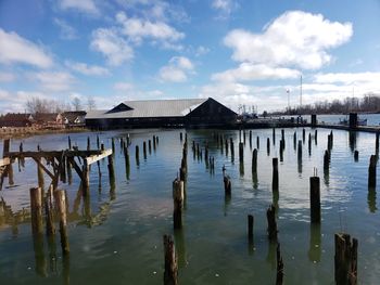 Wooden posts in lake against sky