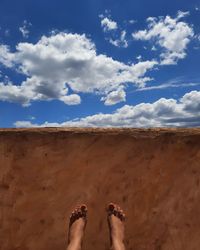 Low section of woman lying on sand against sky