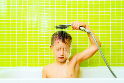 Disgusted expression of a young boy taking a shower and washing himself angrily.