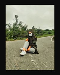 Full length of man sitting on road against sky