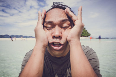 Headshot of man making a face at beach on sunny day