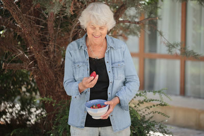 Elderly woman holding a bowl of ripe strawberries