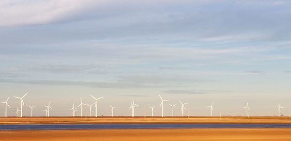 Wind turbines on land against sky