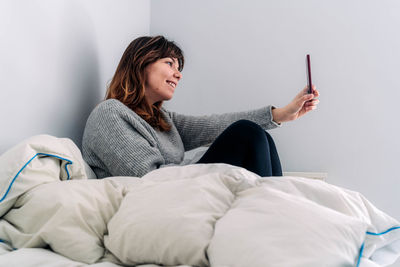 Young woman sitting on bed at home