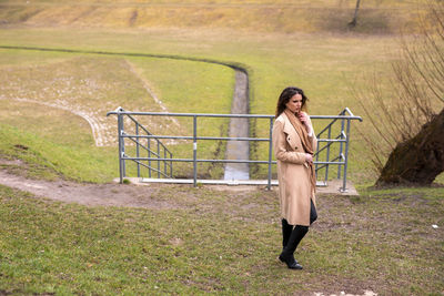 Full length portrait of woman standing on field