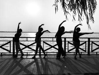 Women with arms outstretched dancing by railing