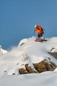 Skier descending above a leap of rock