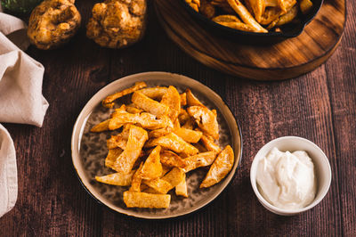 Fried celery root on a plate and sauce in a bowl on the table