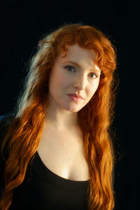 Portrait of young woman against black background