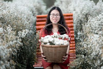 Portrait of woman holding flowers in basket