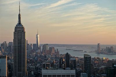 Empire state building in city against sky during sunset