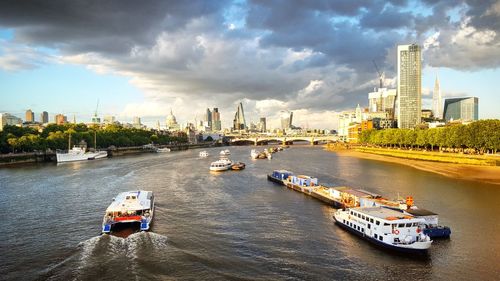 Boats in river against cloudy sky