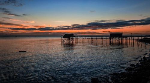 Pier on sea at sunset