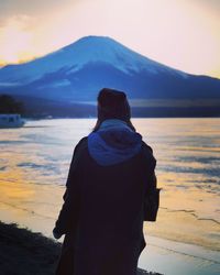 Rear view of man looking at sea against sky