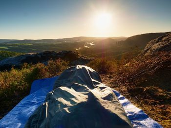 A beautiful awakening in a sleeping bag on a rock ledge. below edge is dark forest with gentle mist.