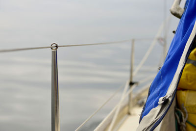 Close-up of rope hanging on railing against sea