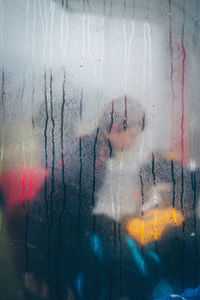 Woman seen through wet glass window